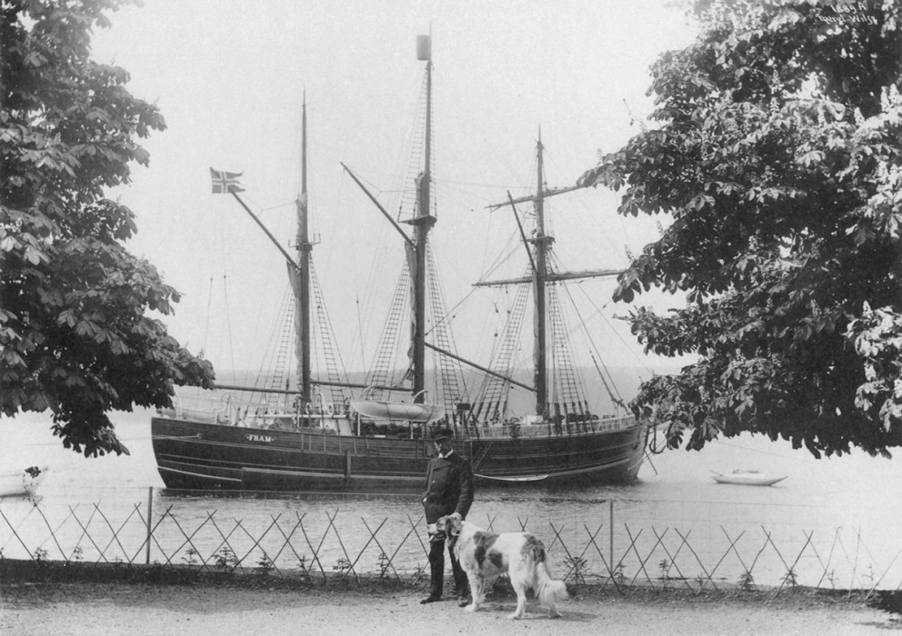 Roald Amundsen med St. Bernhard-hunden sin betrakter Fram som ligger på svai på fjorden utenfor Uranienborg.