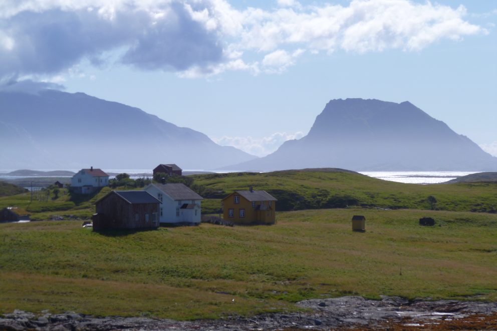 Bilde av vakre Hysvær på Vegaøyan, med slettelandskap i forgrunnen og fjell og hav i bakgrunnen. Foto: J.H. Jørgensen Vegaøyan verdensarv