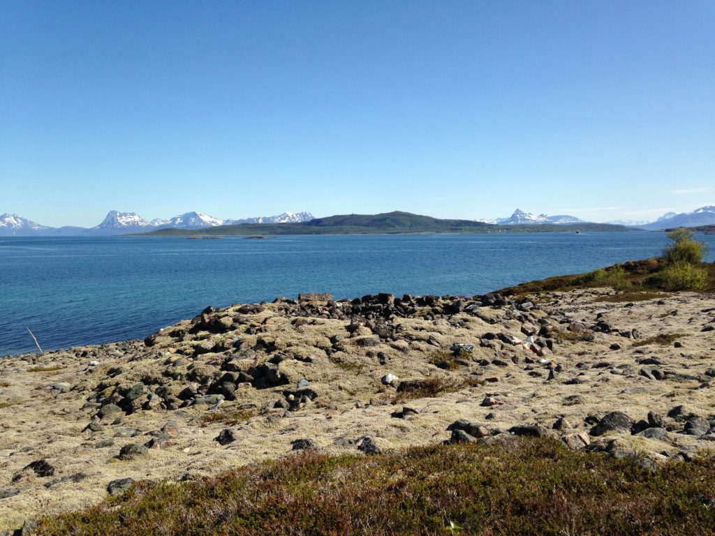 Foto av Bjarkøy. Øde landskap med flere graver. Nærbilde av gravrøys. Foto: Anne Karine Sandmo, Troms fylkeskommune