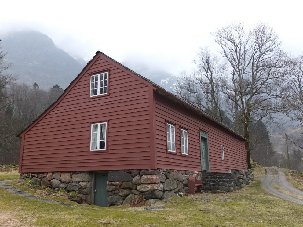 Bilde av Husmannsplassen Treo. Bygningen har rødmalt bordkledning og hvite smårutete vinduer. Bygningen står på gråstenmurte ringmurer og delvis kjellermur. Foto: May Britt Håbjørg, Riksantikvaren