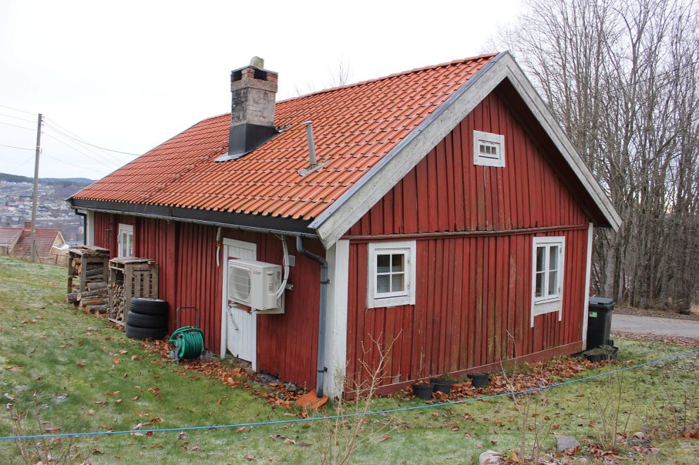 Bildet viser et rødt lite trehus med hvite karmer.