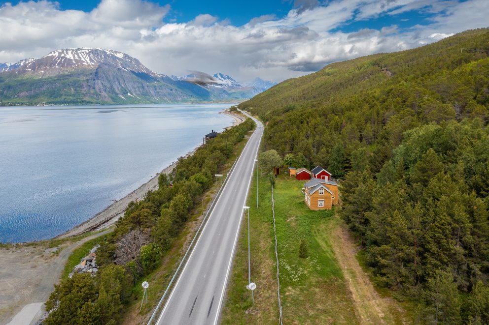 Den kvenske gården Hottitalo / Hottigården med veien og fjæra, sett mot nord med fjell og sjø
