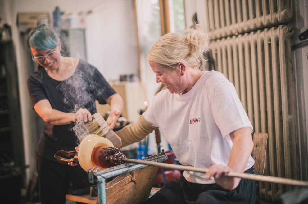 To kvinner som former rykende varmt glass for hånd.