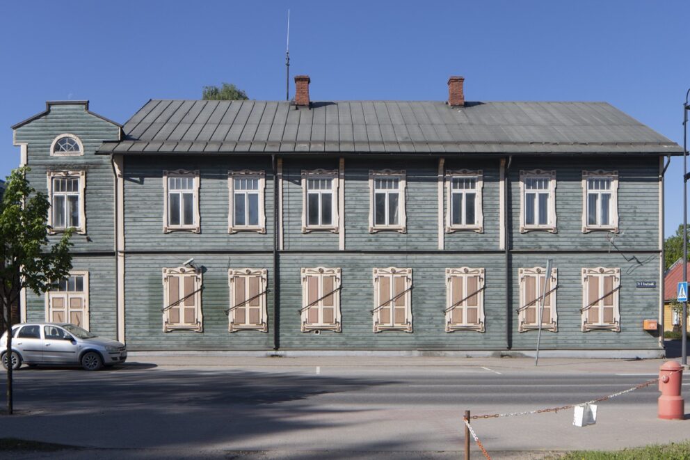 Nærbilde av et slitt inngangsparti, med hvite søyler, sprukken mur og doble dører.
