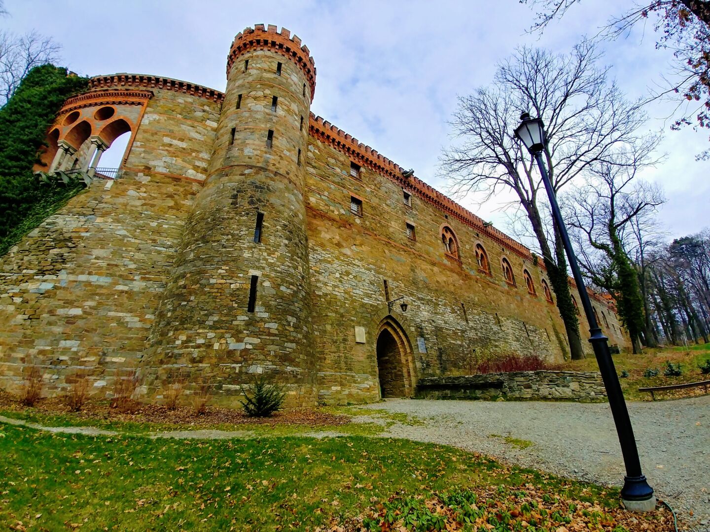 Slottsmur og tårn, med grønn plen og eføy som slynger seg oppover slottsveggen.
