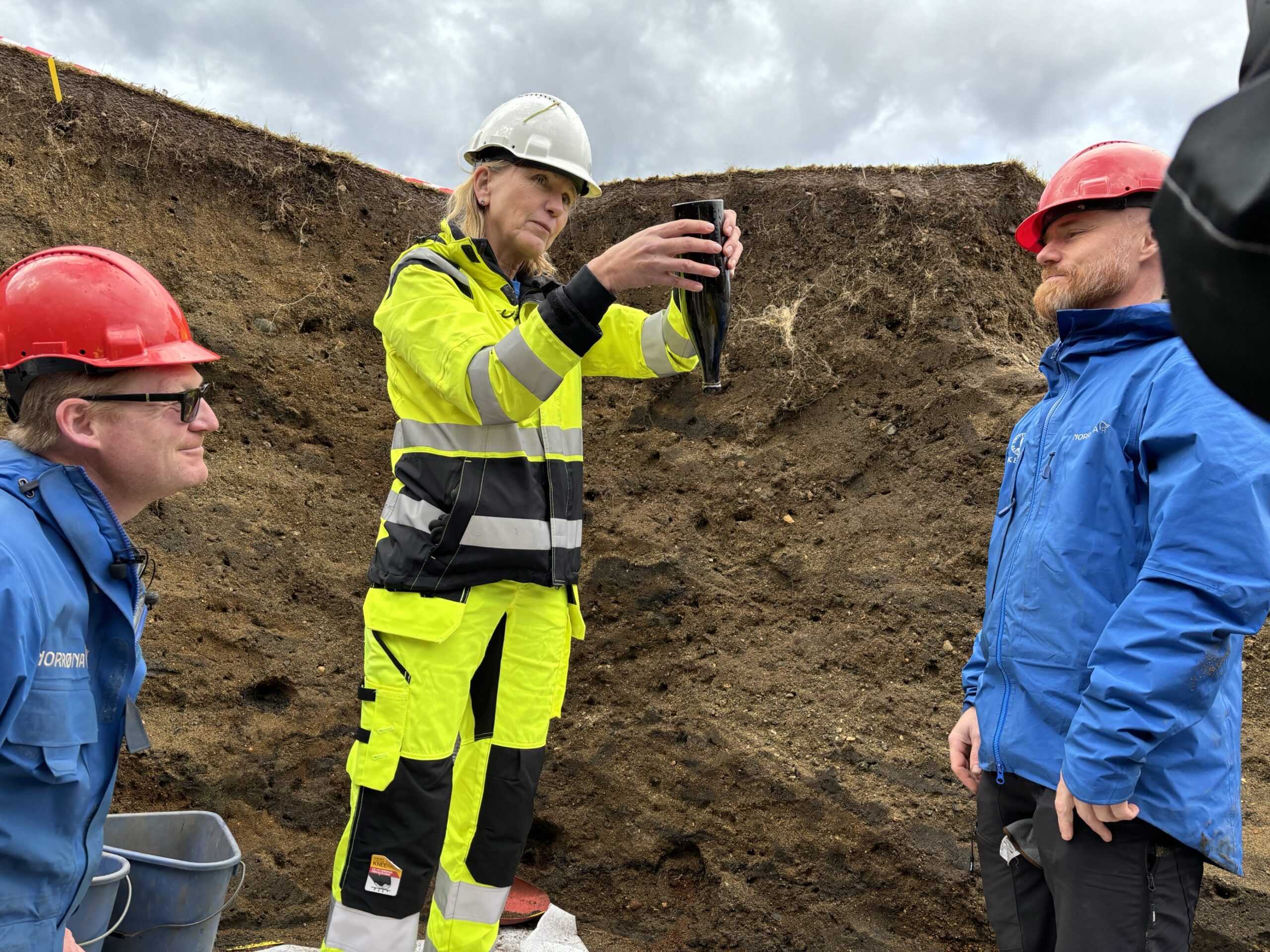 Bilde av arkeologene Morten Ramstad (til venstre) og Thomas Bruen Olsen (til høyre), som flankerer UiB-rektor Margareth Hagen med Anders Loranges flaskepost.