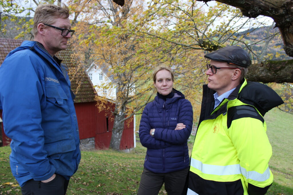 Bilde som viser fra venstre arkeolog Morten Ramstad fra Universitetet i Bergen, riksantikvar Hanna Geiran og seniorrådgiver hos Riksantikvaren, Ole Søe Eriksen, på toppen av Karnilshaugen.