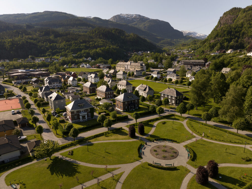 Luftfoto av Åbøbyen i Sauda, som viser boligbebyggelse og skogdekte åser og fjell.