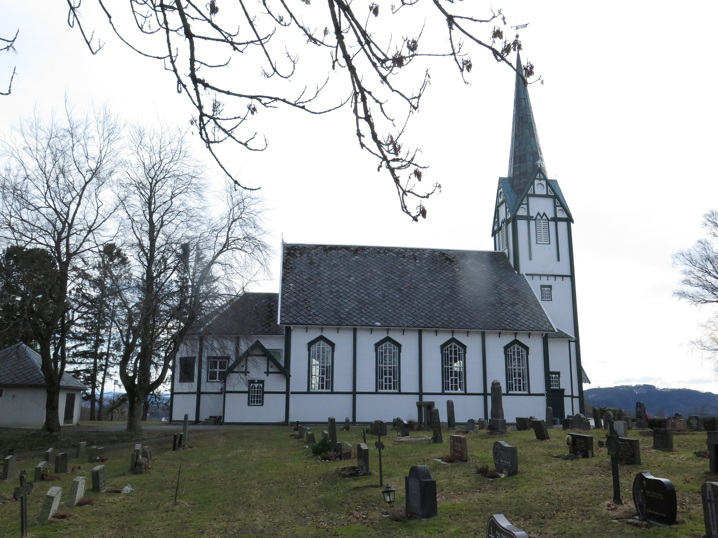 En hvit trekirke med et høyt kirketårn.
