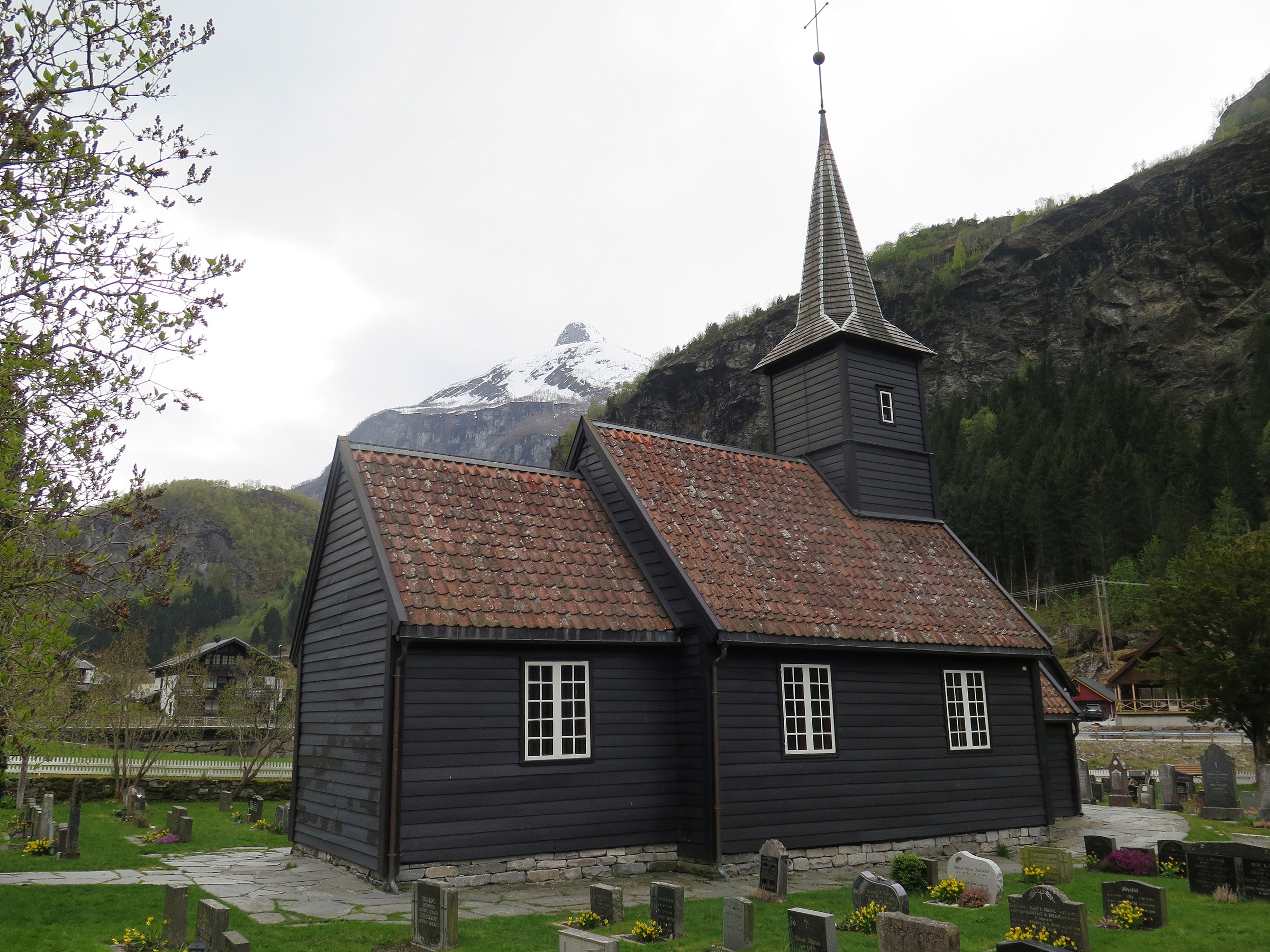 Flåm kirke er en liten trekirke med fjell i bakgrunnen, har fått kirkemidler.