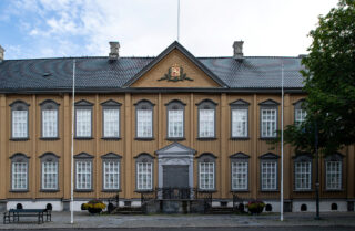 Stiftsgården er en symmetrisk trebygning i to etasjer med mange hvitkalkede vinduer, en sentral inngang og et dekorativt våpenskjold over døren. To tomme flaggstenger står foran.