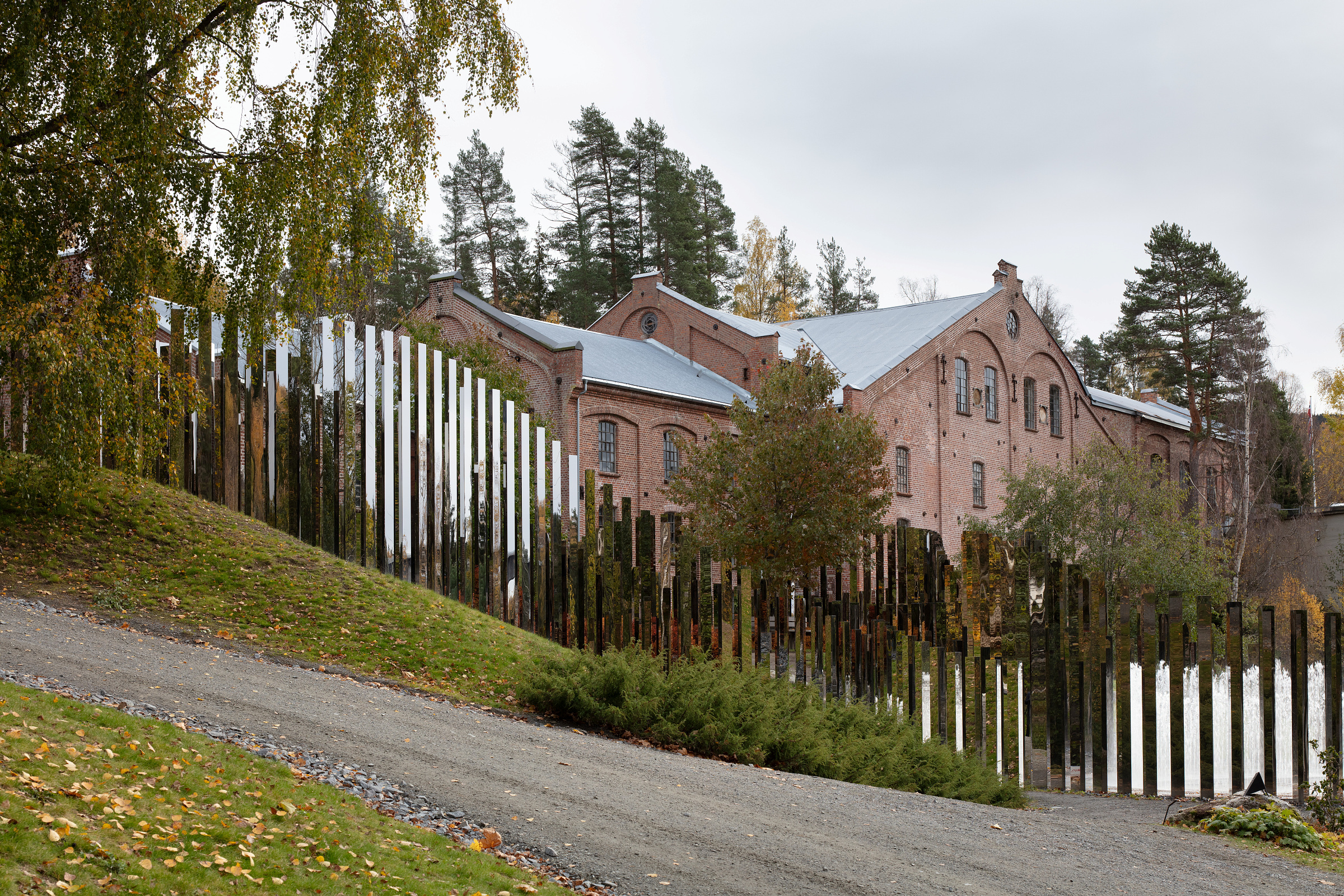 Industribygningen i teglstein står bak en kunstinstallasjon i skråningen.