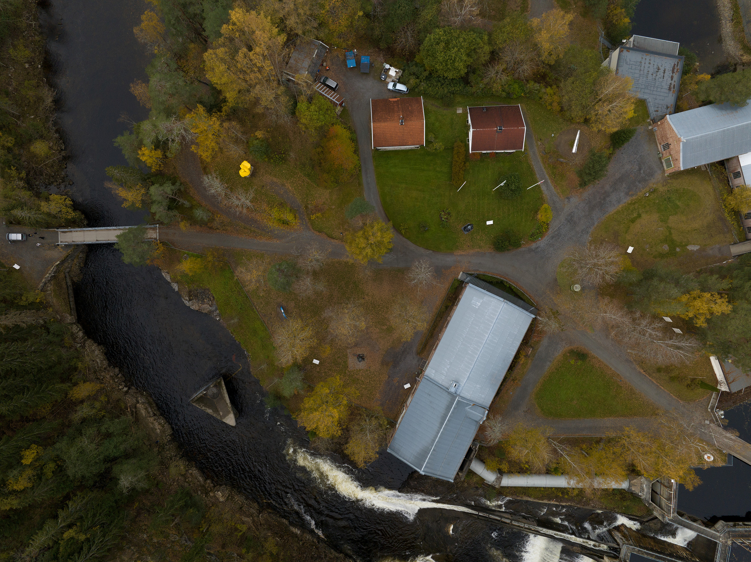 Flyfoto av demningen i Randselva, med bro, stier, og trær