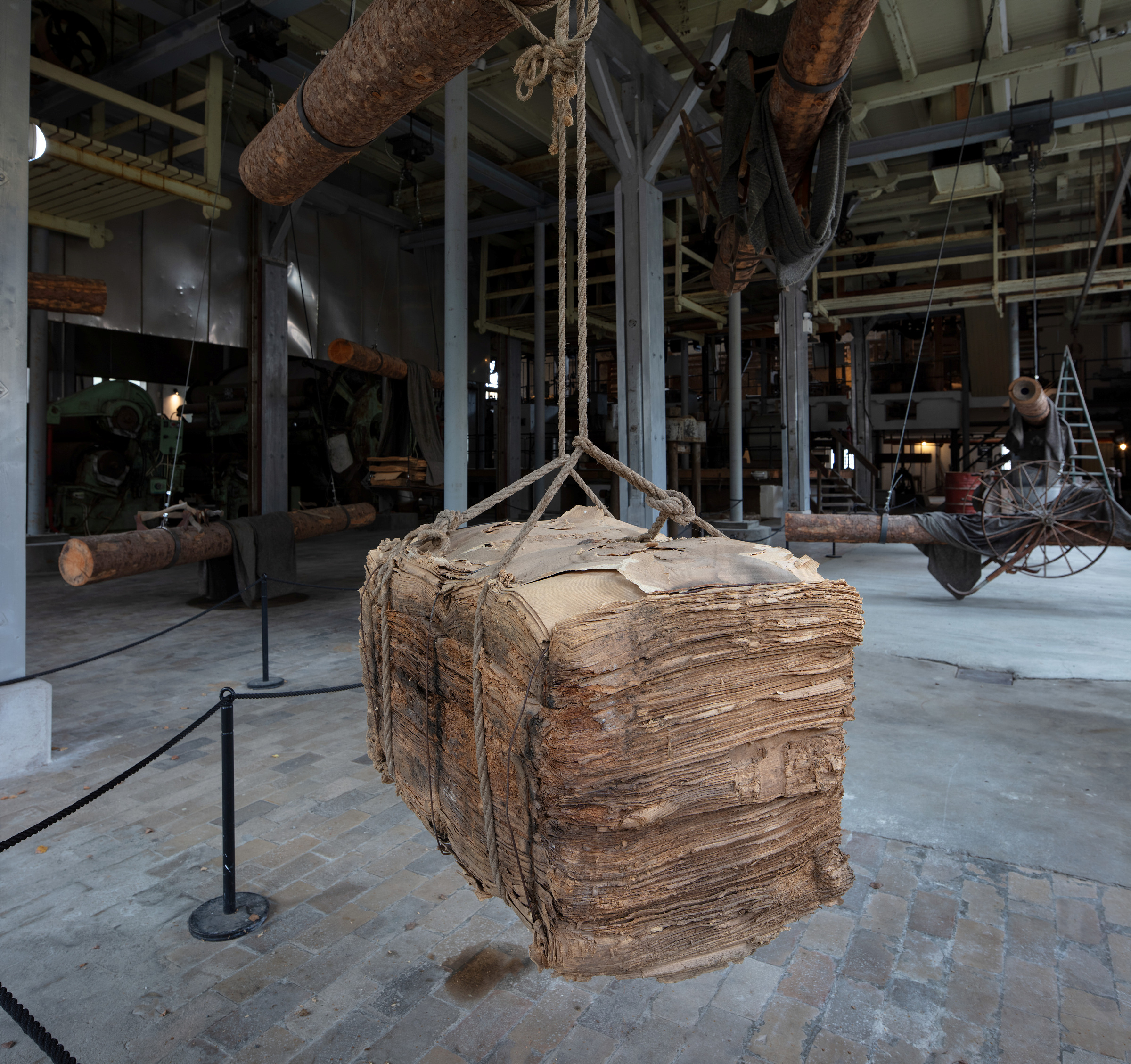 En stor stabel med gammelt, forvitret papir er hengt opp i tau på industrimuseet hos Kistefos Træsliberi.