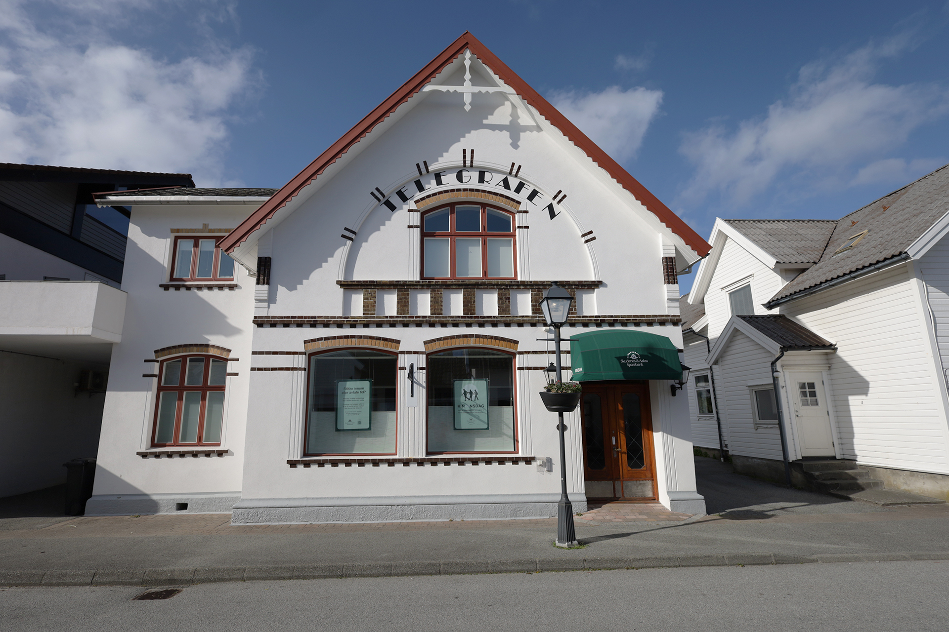 En hvit, toetasjes bygning med buede vinduer, en grønn markise over inngangen og ordet HUBGRABEN på fasaden, sett fra den andre siden av gaten.