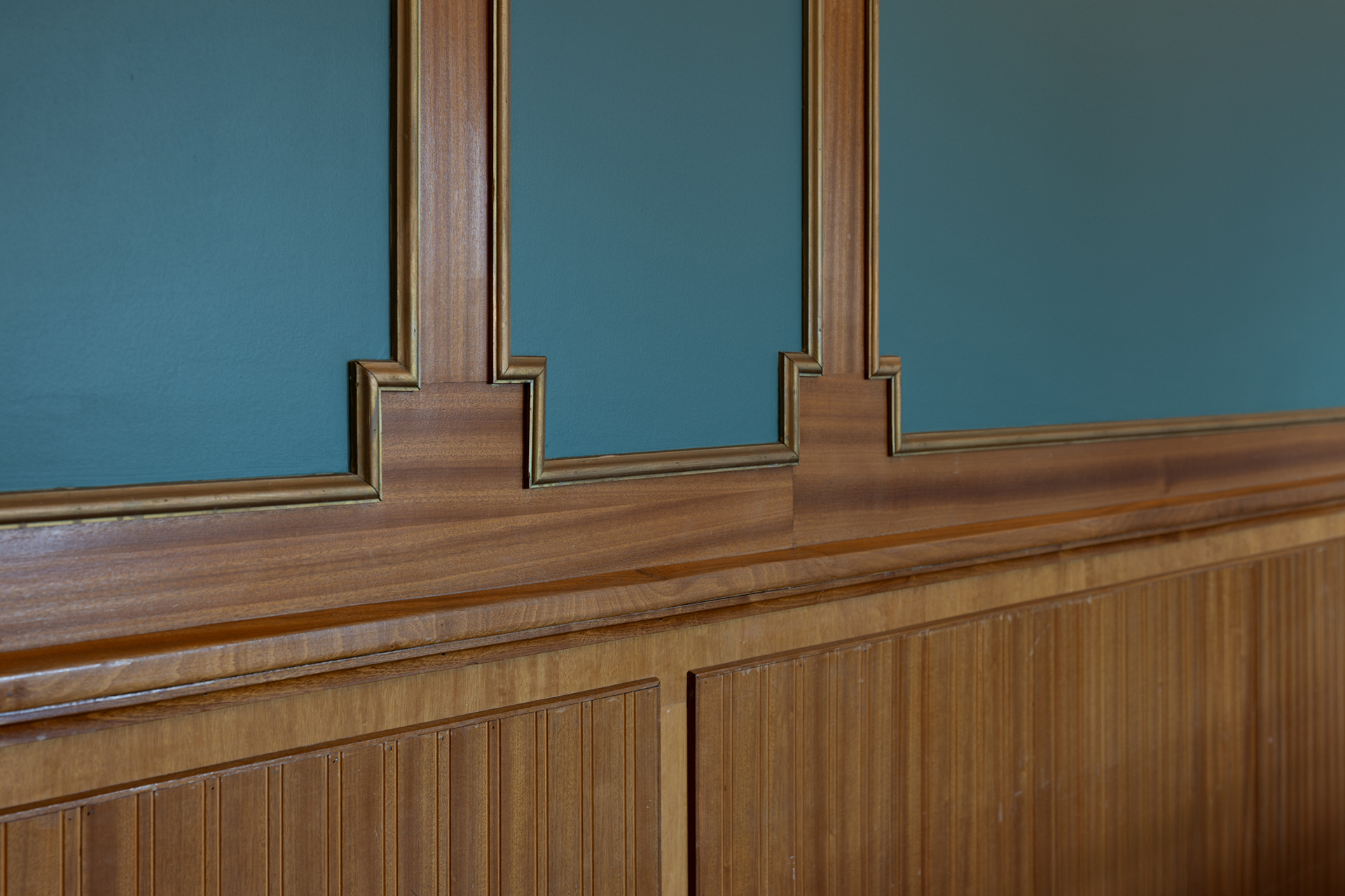 Trepanel med dekorlister dekker den nedre halvdelen av en vegg, mens den øvre delen er malt blå med matchende treverk.