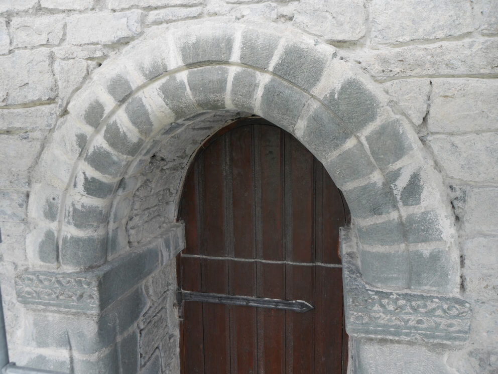 I disse kirkene vil du merke forskjell til jul 8 En buet tredør satt inn i en steinmur med dekorativt steinarbeid rundt inngangen.