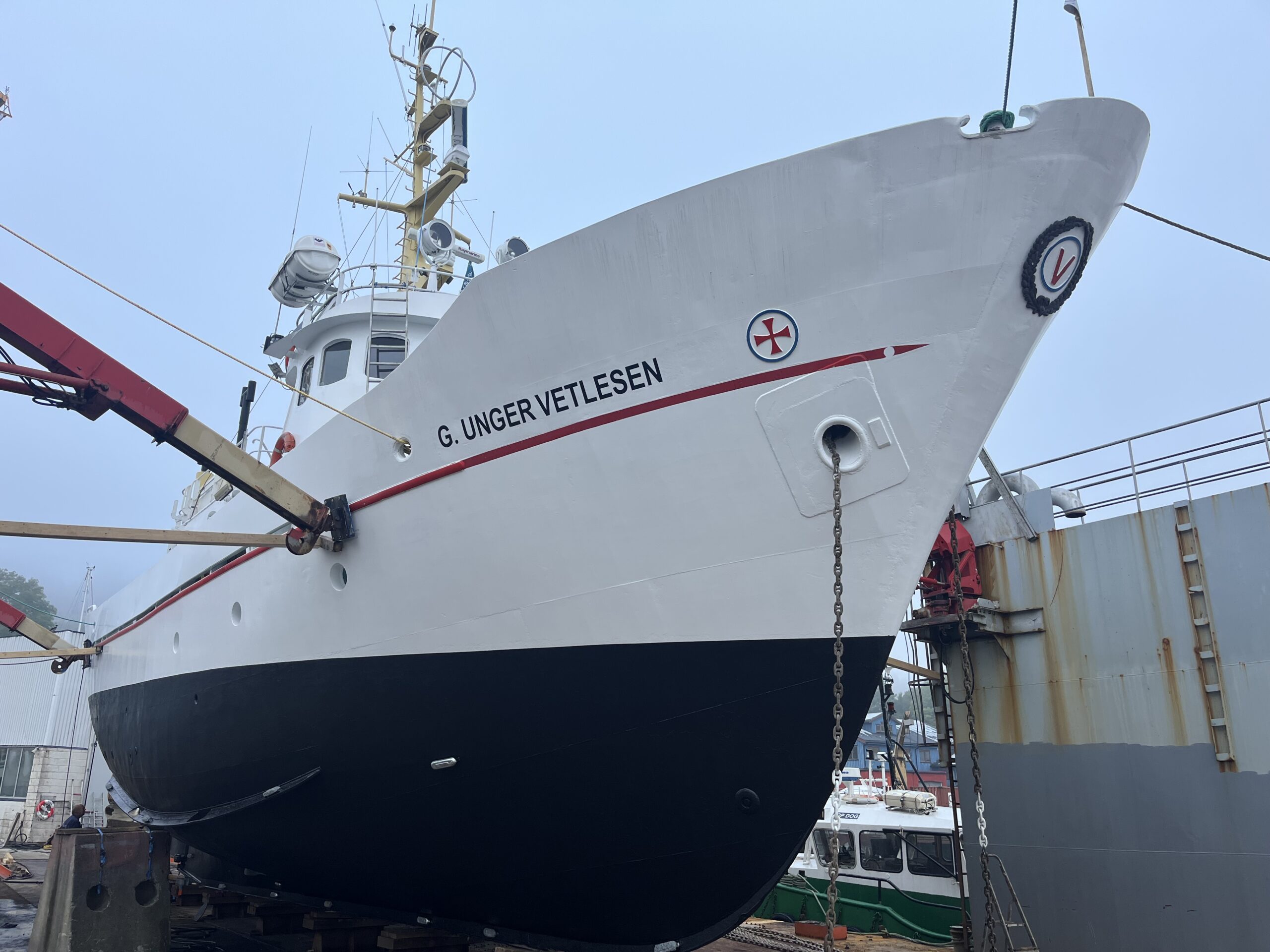 Fartøyvernet får 76 millionar i 2026 1 Et stort, hvitt og svart skip ved navn G. Ungervetlesen ligger til kai på land for vedlikehold, med utstyr og en mindre båt synlig i nærheten.