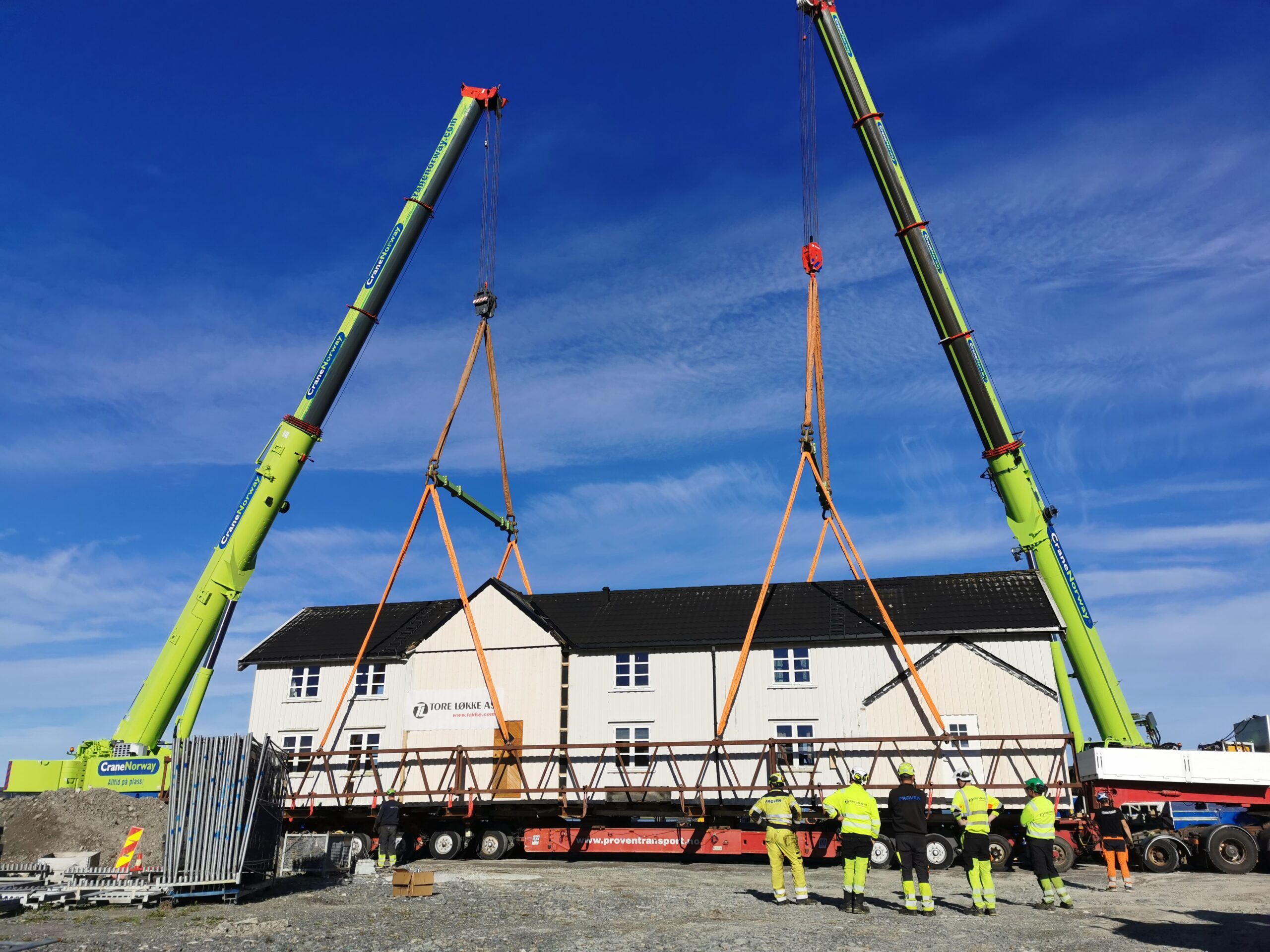 To kraner løfter en hvit bygning.