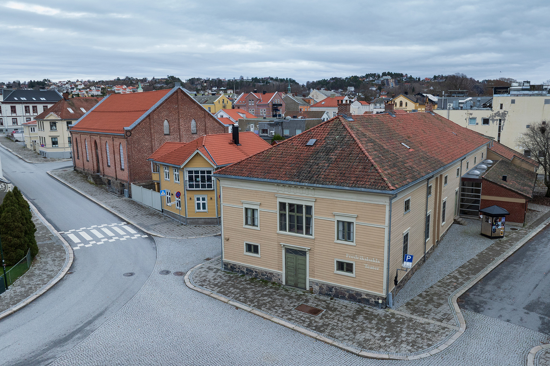 Et stille gatehjørne i en liten by med brosteinsbelagte veier, historiske bygninger og overskyet himmel.