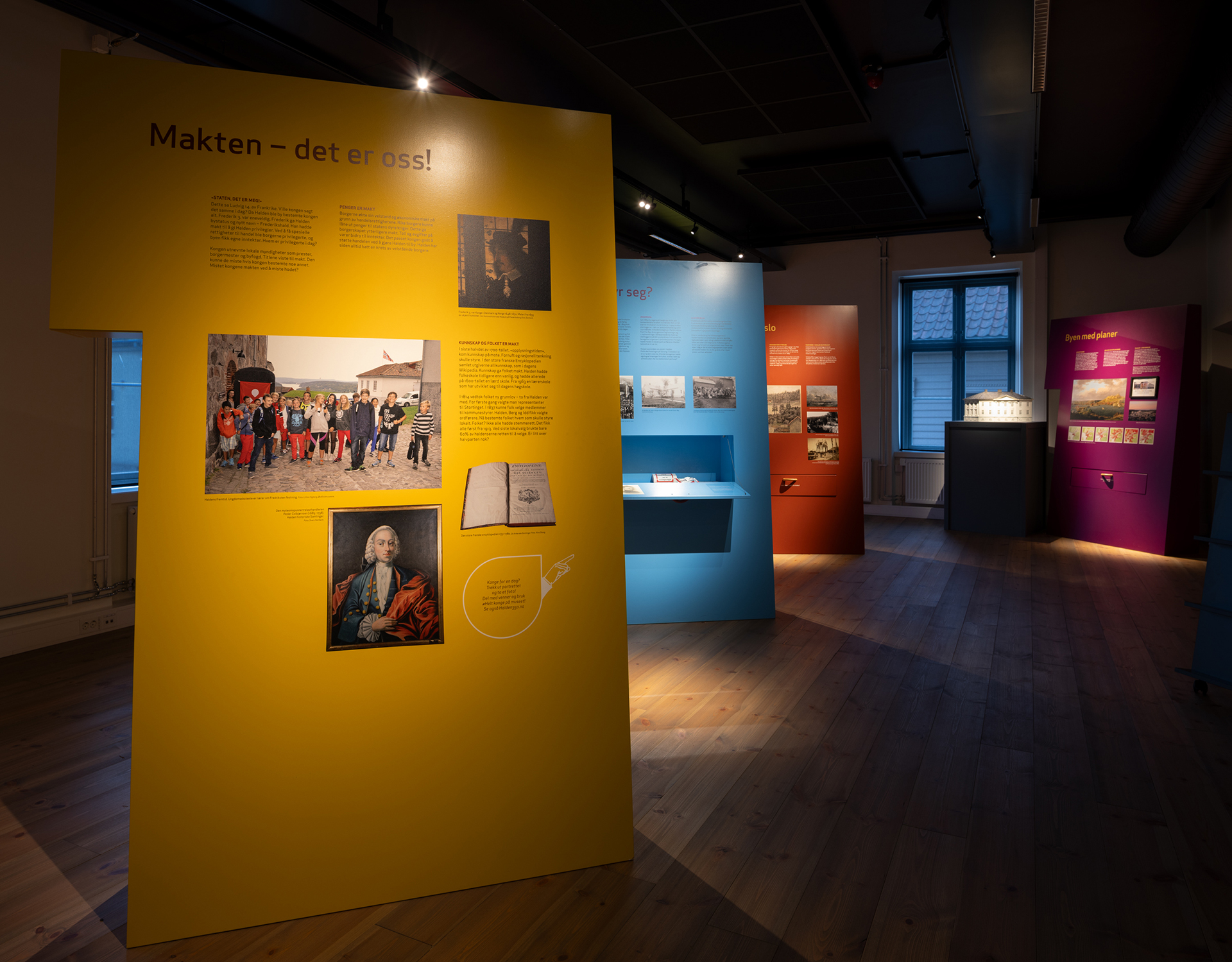 Paleet som opna seg for parken, og for byen 9 Et utstillingsrom med fargerike informasjonstavler og historiske bilder, med en fremtredende gul skjerm med tittelen Makten - det er oss!.