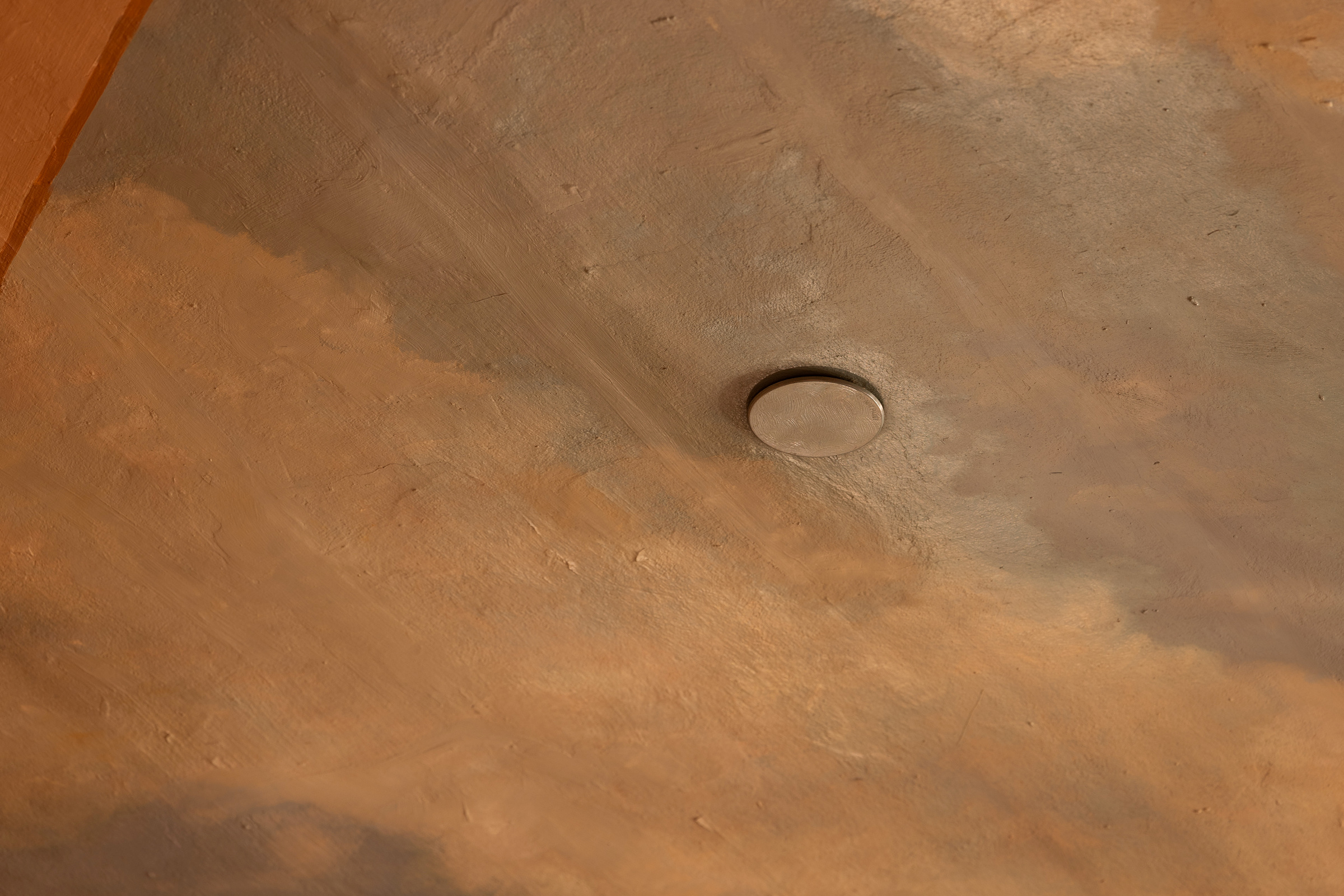 Rigga med både tradisjonelle og moderne løysingar 10 En rund metallknapp er innfelt i en brun og brunbrun overflate, muligens en vegg eller et tak.