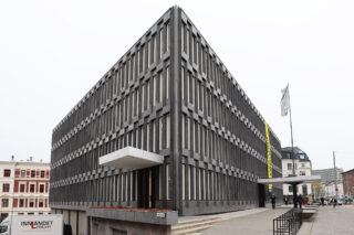 Den tidligere amerikanske ambassaden. En stor, rektangulær, modernistisk bygning med en rutenettlignende fasade med smale, vertikale vinduer og et utkraget inngangstak. Mennesker og et flagg er synlige på utsiden.