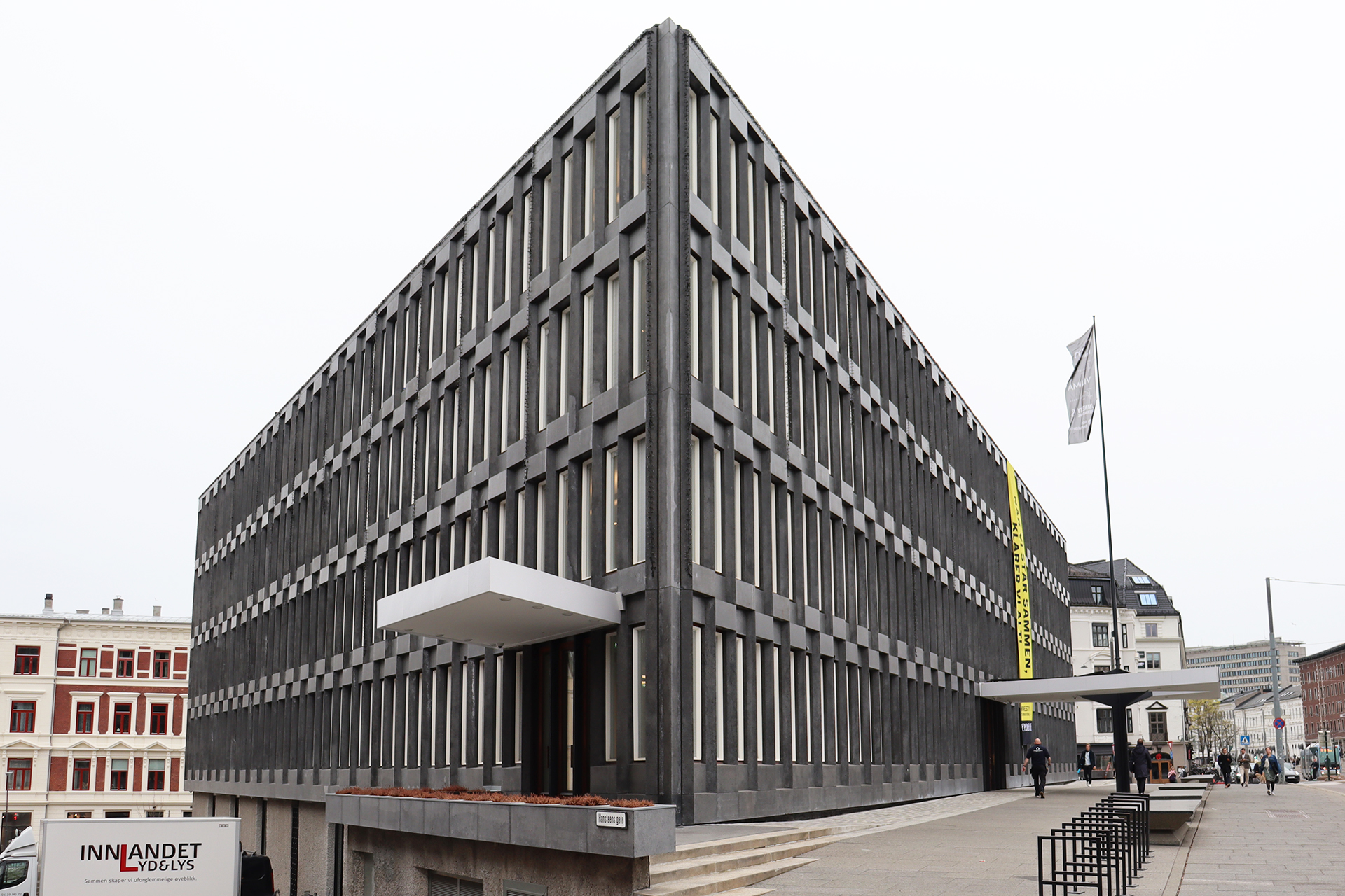 Høstmøtet 2026 6 Den tidligere amerikanske ambassaden. En stor, rektangulær, modernistisk bygning med en rutenettlignende fasade med smale, vertikale vinduer og et utkraget inngangstak. Mennesker og et flagg er synlige på utsiden.