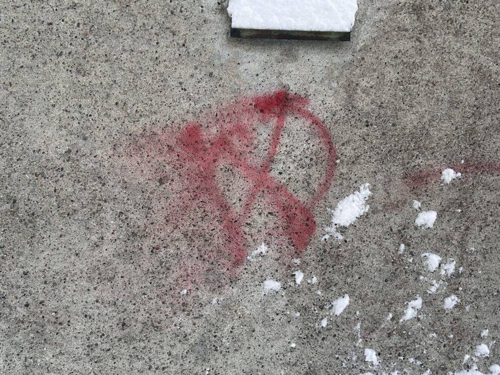 Rødt sprayet hammer og sigd-symbol på en betongvegg med snøflekker i nærheten.