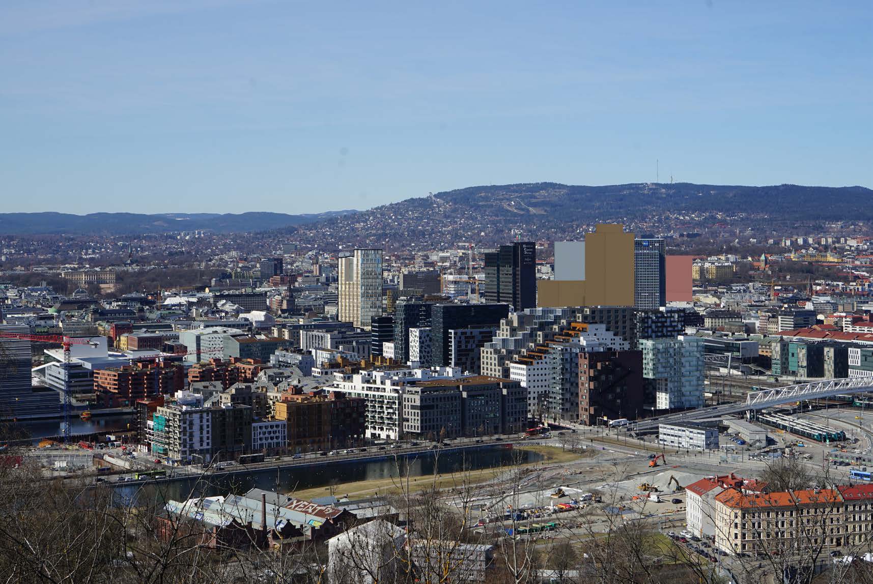 Byutsikt over et moderne byområde med høyhus, veier og omkringliggende åser under en klar himmel.
