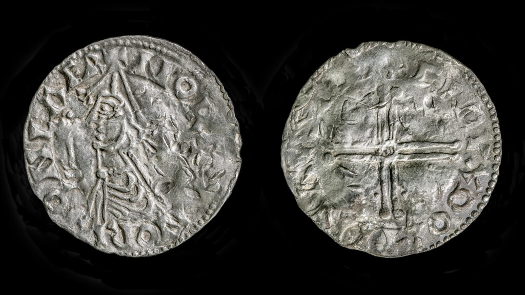 Forsiden og baksiden av en slitt middelaldersk sølvmynt, som viser en figur med en stav på den ene siden og et kors på den andre.